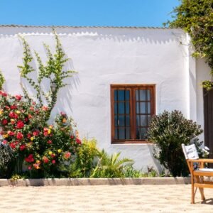 Whitewashed house with colorful flowers and outdoor seating in Algarrobo, Chile.